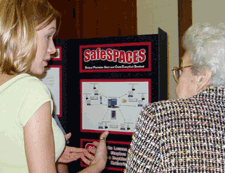 Photo of Katherine Raynor explaining her team's SafeSPACES project to a visitor at the Spring 2004 Posters & Pies.